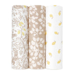 Three rolls of fabric stand upright: the left displays a bamboo-infused viscose with gray and yellow floral and animal patterns, the middle has a beige background with white leaves, and the right features an aden + anais boutique silky soft swaddle blanket on a white backdrop with yellow leaves.