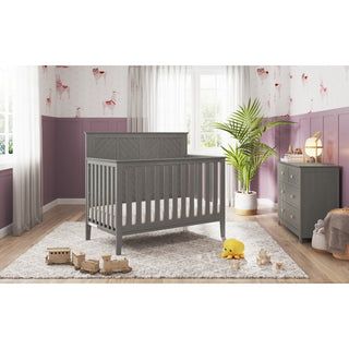 The Atwood Crib Nursery Bundle by HALO creates a cozy nursery with a convertible crib, organic cotton sheets, plush rug, wooden toys, stuffed duck, dresser, and plant. Purple walls, animal wallpaper, and large windows fill the space with light.