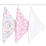 Three aden + anais boutique 100% cotton muslin oversized washcloths hang from a rod: one with a pink and green floral pattern ideal for delicate skin, another featuring pink with white floral designs, and the third is white adorned with small pastel dots, all ensuring comfort during tender moments.