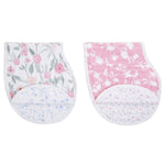 The aden + anais boutique 100% cotton muslin burpy bibs 2 pack showcases two floral-patterned cloths: an absorbent muslin one with pink and green flowers, and a no-slip bib featuring pink and white blooms. Both have rounded corners with extra fabric layers adorned with smaller floral designs.