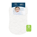 A white, moon-patterned HALO BassiNest® DreamWeave Breathable Pad is shown with its packaging featuring a smiling baby. A GREENGUARD Gold label at the bottom right highlights its breathable and hypoallergenic qualities.