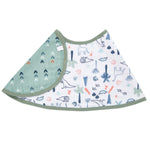 The aden + anais essentials cotton muslin burpy bib features a whimsical dinosaur theme on white with blue, green, and orange dinosaurs and plants. Its made from absorbent muslin with a light green reverse side featuring gray and orange arrows, accentuated by charming green trim.