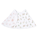 The aden + anais essentials cotton muslin burpy bib features a soft, white backdrop adorned with delicate pink and green floral patterns, showcasing its full coverage design against a plain white background.