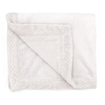 A folded essentials plush blanket by aden + anais, featuring a textured border, is shown on a white background. One corner is turned over to unveil the plush inner layer.