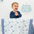 A smiling toddler in a navy shirt stands in a crib, clapping hands. Draped over the cribs edge is an aden + anais essentials cotton muslin bedding set with blue and green animal prints. A testimonial reads: Very soft and gets even softer when washed and dried. I highly recommend it.