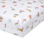 The aden + anais essentials cotton muslin crib sheet showcases a cheerful circus scene with elephants on balls, seals, and monkeys. Its vibrant illustration adds a festive touch to nursery decor.