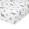 Close-up of the aden + anais essentials cotton muslin crib sheet in white, featuring a playful dinosaur pattern in green, brown, and blue with trees and foliage. Fits standard crib mattresses perfectly.