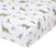 Close-up of the aden + anais essentials cotton muslin crib sheet in white, featuring a playful dinosaur pattern in green, brown, and blue with trees and foliage. Fits standard crib mattresses perfectly.
