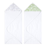 Two aden + anais essentials cotton muslin hooded towels: one with a blue and green leaf pattern hood, the other featuring white animal and tree silhouettes on a green background.