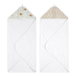The aden + anais essentials cotton muslin hooded towels 2 pack includes two white towels: one with green elephants and another with a beige zigzag, made from plush cotton terry for maximum absorbency. Both offer cozy corners ideal for wrapping up little ones.