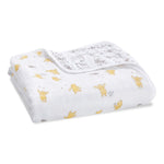 The aden + anais Disney™ Winnie the Pooh essentials cotton muslin dream blanket is a folded white baby blanket featuring yellow Pooh designs and subtle gray patterns inside.