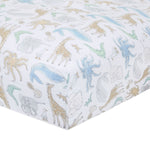 The aden + anais essentials cotton muslin crib sheet features hand-drawn animals like giraffes, elephants, and alligators in pastel colors—blue, green, and beige—on cozy white cotton muslin. These whimsical nursery prints are scattered across the fabric.