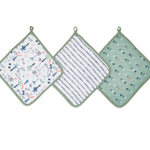 Three essential cotton muslin washcloths by aden + anais: the left with whimsical animal and plant prints, the middle in navy stripes, and the right featuring a subtle sage green leaf design, all with absorbent layers and hanging loops.