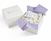 A white Gift Box by HALO, partially open with purple tissue paper, reveals a folded white baby blanket featuring blue trim and a lemon print.