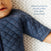 A baby in a blue quilted garment rests on a patterned surface; the text reads, Sleeves prevent startle reflex (but allow movement). The HALO Easy Transition SleepSack TOG 1.5 ensures better sleep and eases the infants transition.