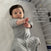 A dark-haired baby in a gray Easy Transition SleepSack TOG 1.5 by HALO lies wide-eyed in a crib. Text beside reads: From the first night, this 3-layer design ensured he slept the whole night through. I need to buy 3 more! —Jennifer.