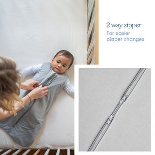 A woman zips up a gray HALO SuperSoft Bamboo Wearable Blanket TOG 1.5 on a baby in a crib. An inset highlights the 2-way zipper with text: “2-way zipper. For easier diaper changes.”.