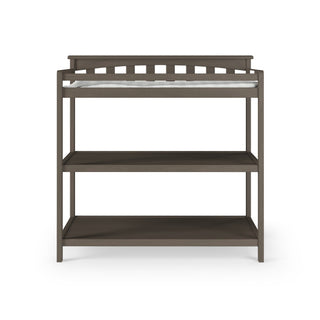 The Child Craft London 2-Piece Nursery Set features a wooden changing table with two open shelves and a raised slatted back, making it an essential addition to any nursery. Shown against a white background.
