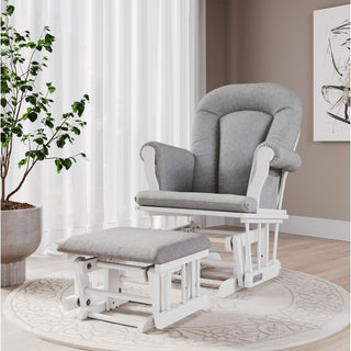 A Child Craft Scout 4 Piece Nursery Set, featuring a gray upholstered glider chair with matching ottoman, rests on a round patterned rug beside a large potted plant and sheer white curtains in a softly lit, modern room—perfectly complementing the elegant nursery furniture.