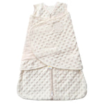 The HALO Swaddle Plushy Dot Velboa TOG 3.0 is a cream-colored, sleeveless SleepSack® with a soft, dot pattern. It features a bottom zip closure, adjustable wings for healthy hip development, and an embroidered logo on the wrap-around flap.
