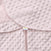 A close-up of the Swaddle Plushy Dot Velboa TOG 3.0 baby blanket shows its soft, textured pink fabric with small circular bumps. It features a HALO tagged zipper pull and adjustable wings, designed for healthy hip development as part of the HALO SleepSack® Swaddle collection.