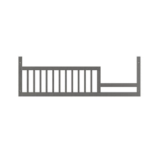 The Child Craft F09503 Toddler Guard Rail in Midnight Gray is a horizontal metal rail with vertical bars and mounting holes, designed to attach to the side of a bed or crib to help prevent toddler falls.