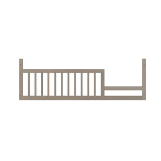 The Child Craft F09503 Toddler Guard Rail in Crescent Grey features vertical slats and mounting brackets, designed for secure attachment to a Child Craft crib as a toddler guard rail for added safety.